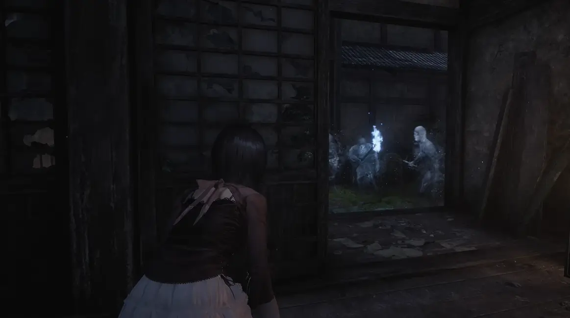 A protagonista de Fatal Frame II Remake observa furtivamente Onis ao fundo, em uma vila sombria, pronta para capturá-los com a Camera Obscura.