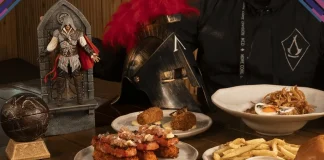 Imagem de destaque mostrando o personagem icônico posando em frente a uma mesa repleta de pratos temáticos do evento oficial de Assassin’s Creed no Restaurante Xepa.