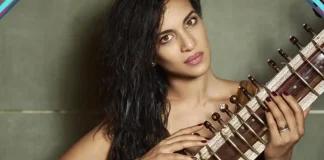 Anoushka Shankar toca sitar durante apresentação ao vivo em palco iluminado