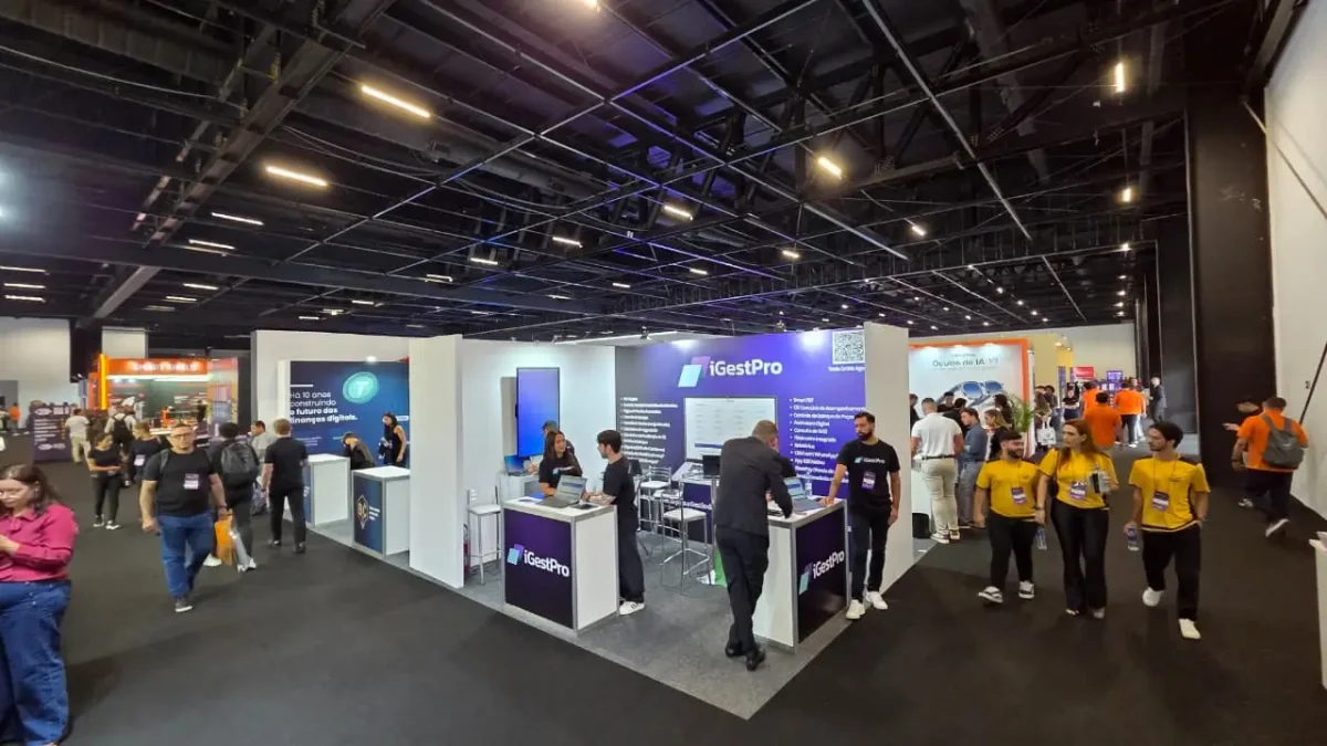 Corredor movimentado com visitantes e estandes de tecnologia durante evento do setor mobile