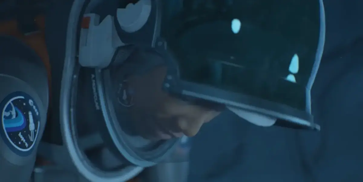 Aphelion é lançado hoje: a maior aposta da DON'T NOD desde Life is Strange 3 Close no capacete de Ariane com patch da missão Hope-01 da ESA no ombro em Aphelion, jogo sci-fi da DON'T NOD