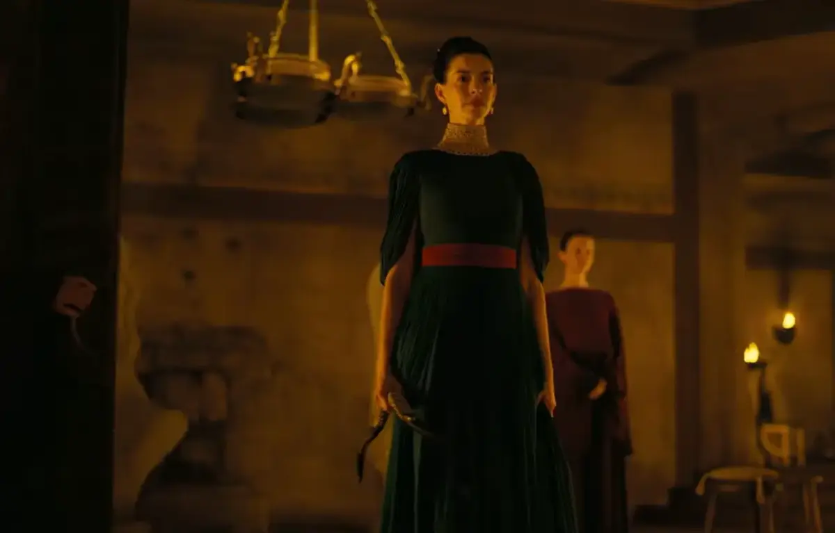 Novo trailer de A Odisseia mostra Odisseu tentando voltar para casa 2 Anne Hathaway como Penélope em vestido verde e faixa vermelha em salão de pedra iluminado a velas no trailer de A Odisseia