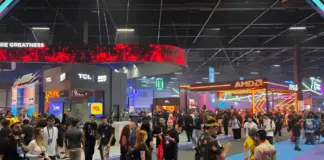 Estandes com iluminação neon e efeito cyberpunk no corredor da gamescom latam 2026 com visitantes transitando pelo evento