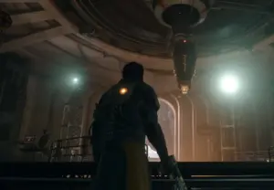 Cena de exploração interna em Saros para PS5, mostrando Arjun Debrage percorrendo um corredor da nave com atmosfera sombria e iluminação em tons alaranjados.