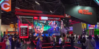 Visão geral do estande da Riot Games na gamescom latam 2026 com telão central exibindo League of Legends, cosplayers no palco e painel de agenda das ativações do dia