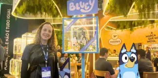 Susan Cavallin posando no estande da Andorinha na APAS Show 2026 com vitrine da edição especial do azeita da Bluey e personagens ao redor