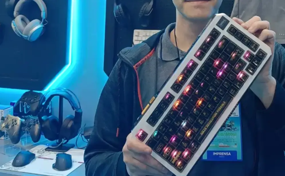 Jefão Calheiro segura periféricos gamers durante a Eletrolar Show, incluindo teclado, headset, mouse, controle e bolsa. Como referência para Eletrolar Show 2026.